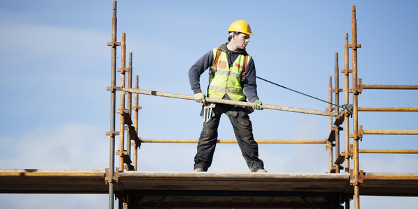 Construction worker setting up scaffolding against the sky